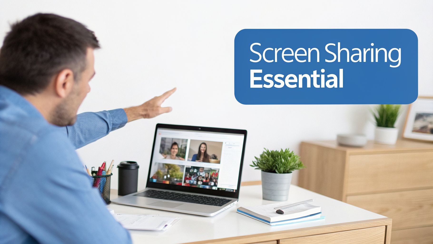 Man in blue shirt points at laptop showing a video conference with multiple participants and screen sharing.