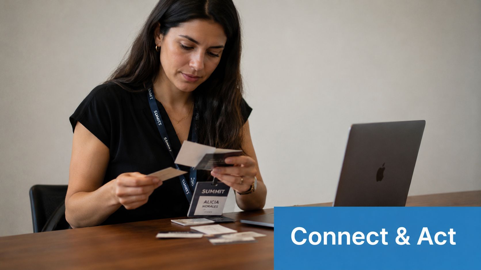 A professional woman organizing business cards at a desk with a laptop after a networking conference.